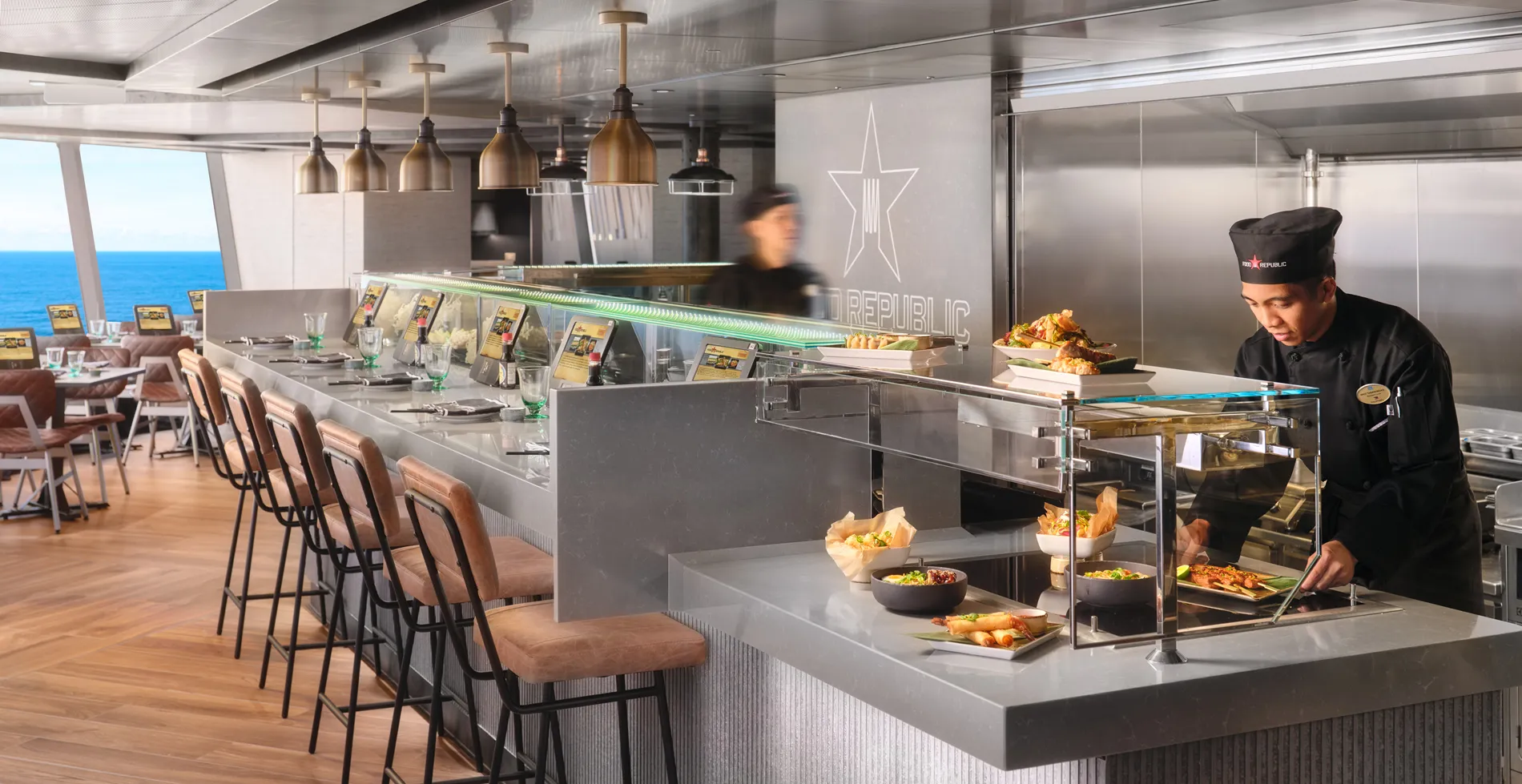 Modern restaurant kitchen with ocean view and chef preparing meals