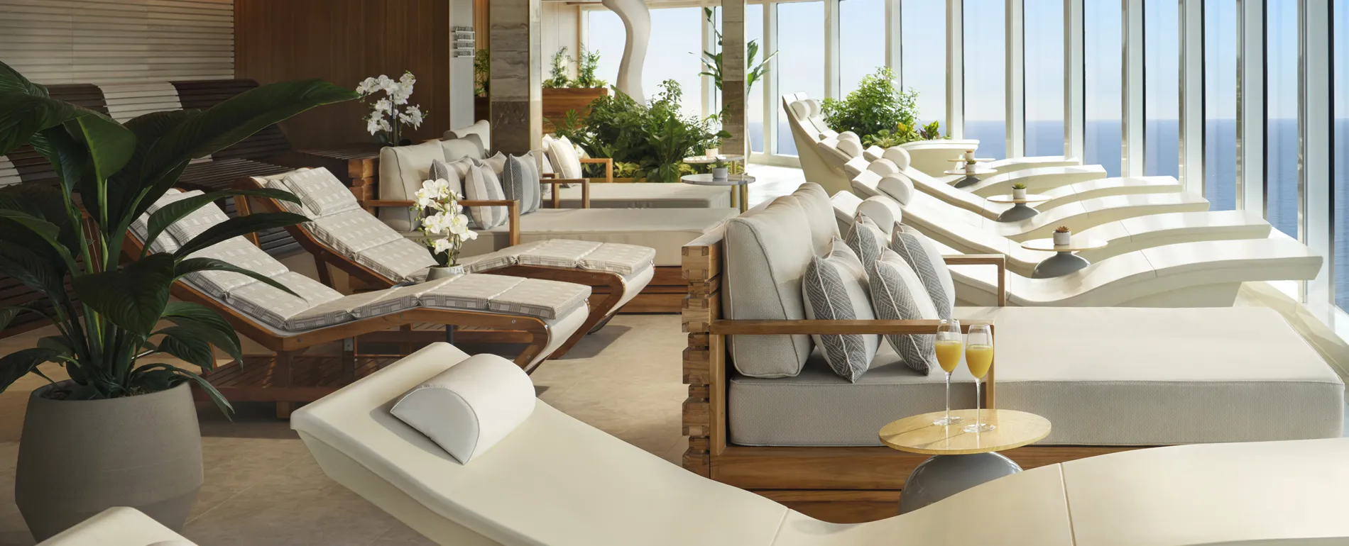 Luxurious spa lounge with white loungers, ocean view, and champagne glasses