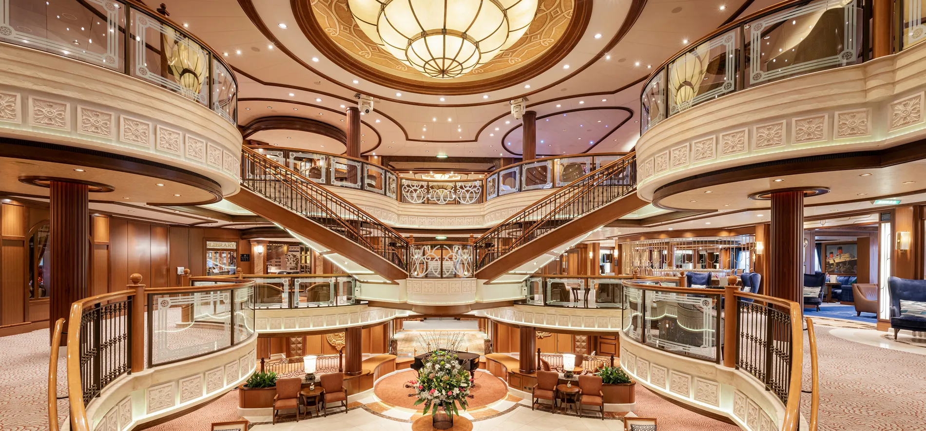 Luxurious multi-level cruise ship interior with grand chandelier and staircases