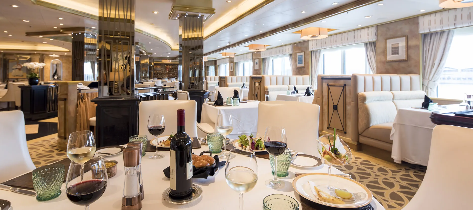 Elegant dining room with white tables, wine glasses, and gourmet dishes