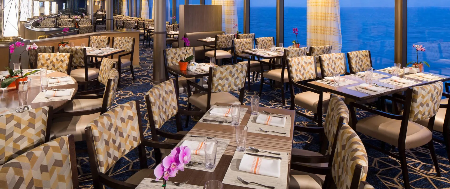Elegant cruise ship restaurant with ocean view and pink orchid centerpieces