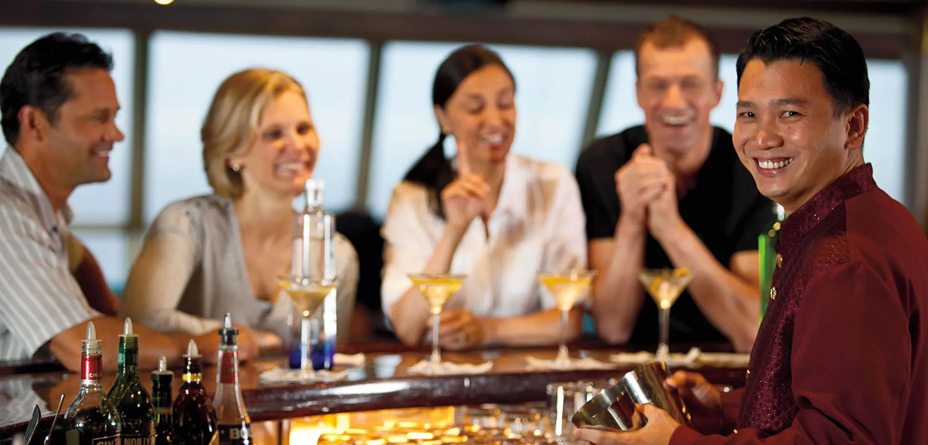 Smiling bartender and friends enjoying cocktails at a bar together