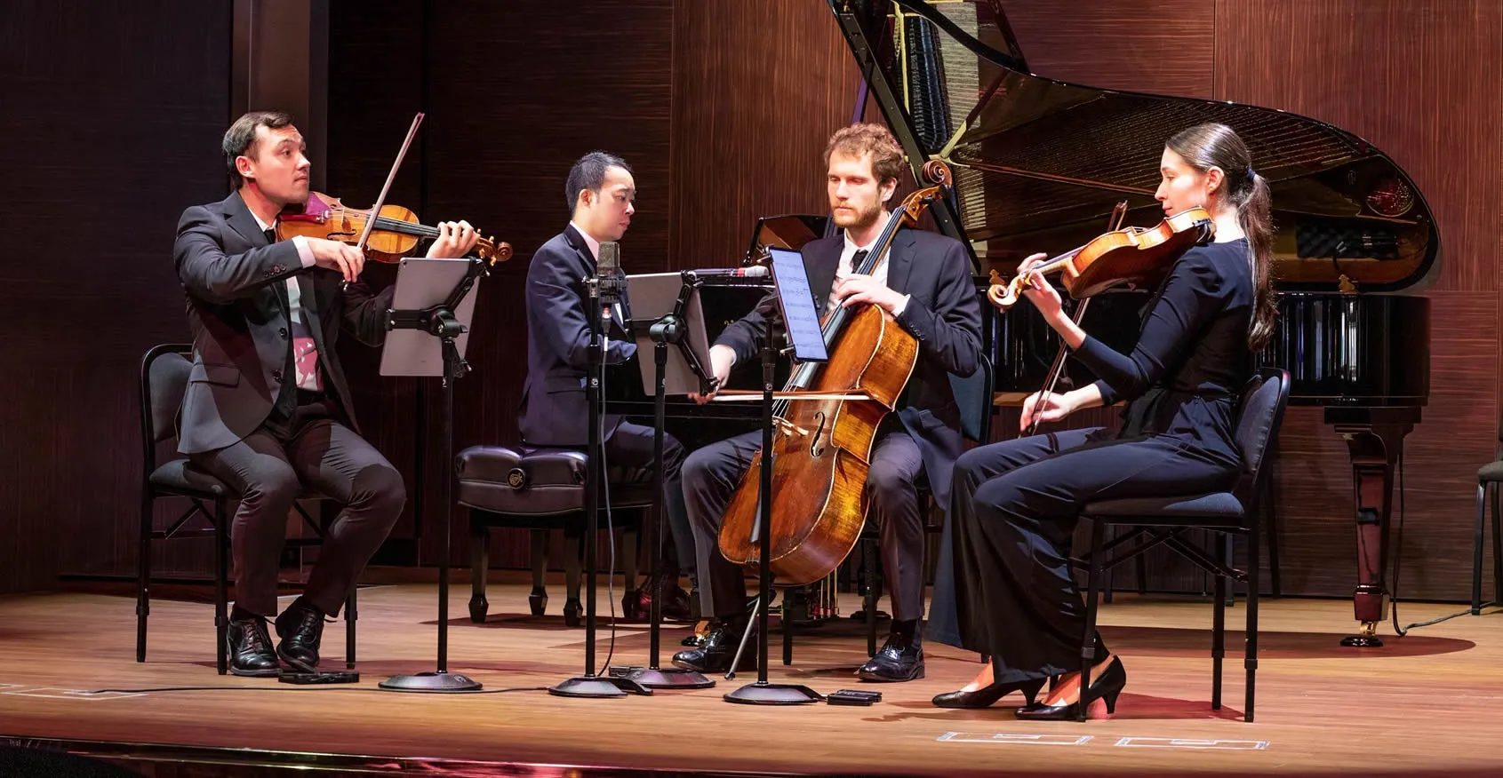 Classical music ensemble performing string quartet with piano on stage