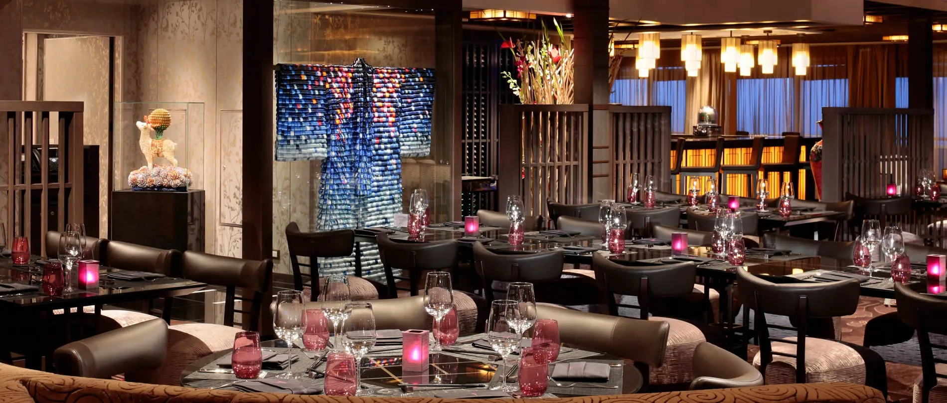 Elegant restaurant interior with pink candles, glassware, and blue artistic backdrop