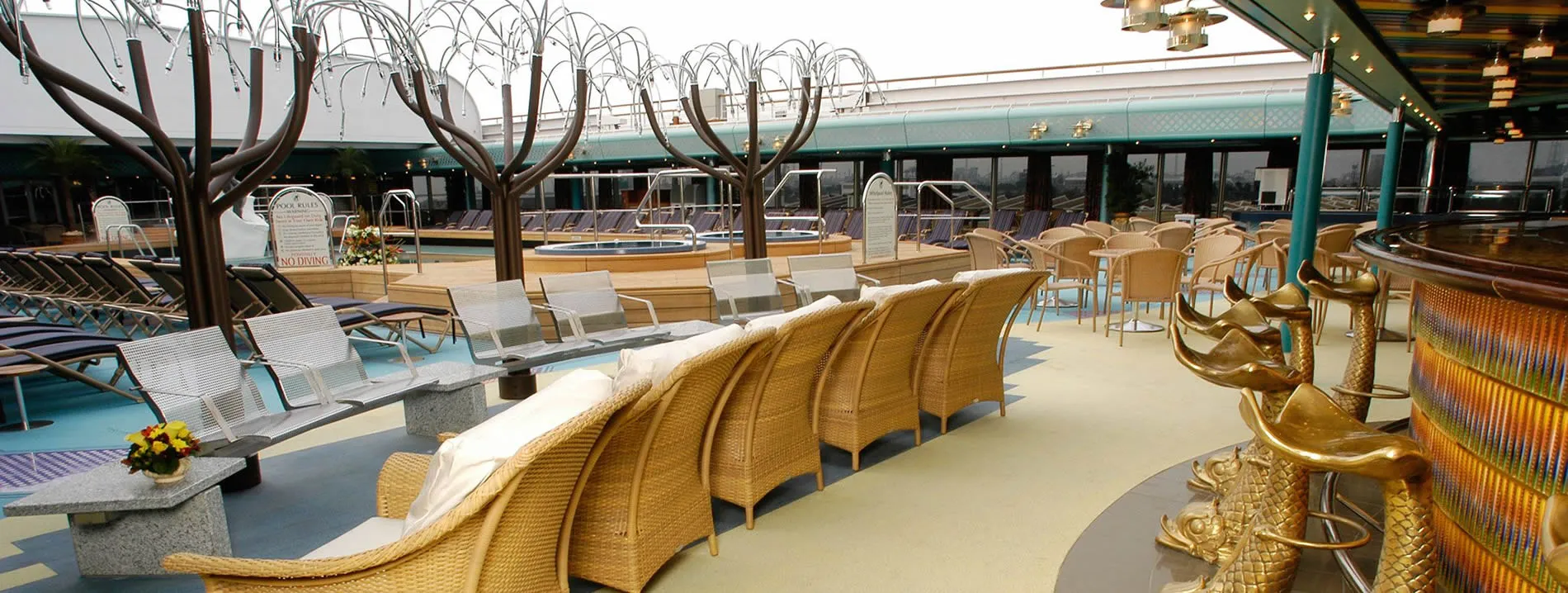 Cruise ship deck with golden chairs, decorative trees, and empty lounging area