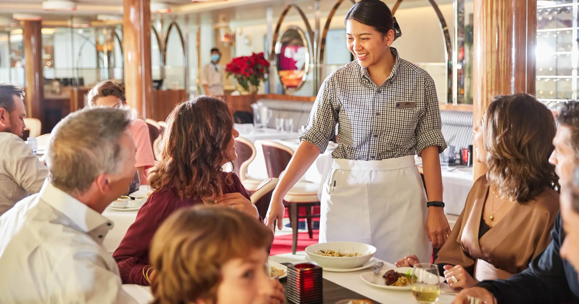Smiling waitress serving customers in an elegant restaurant dining room
