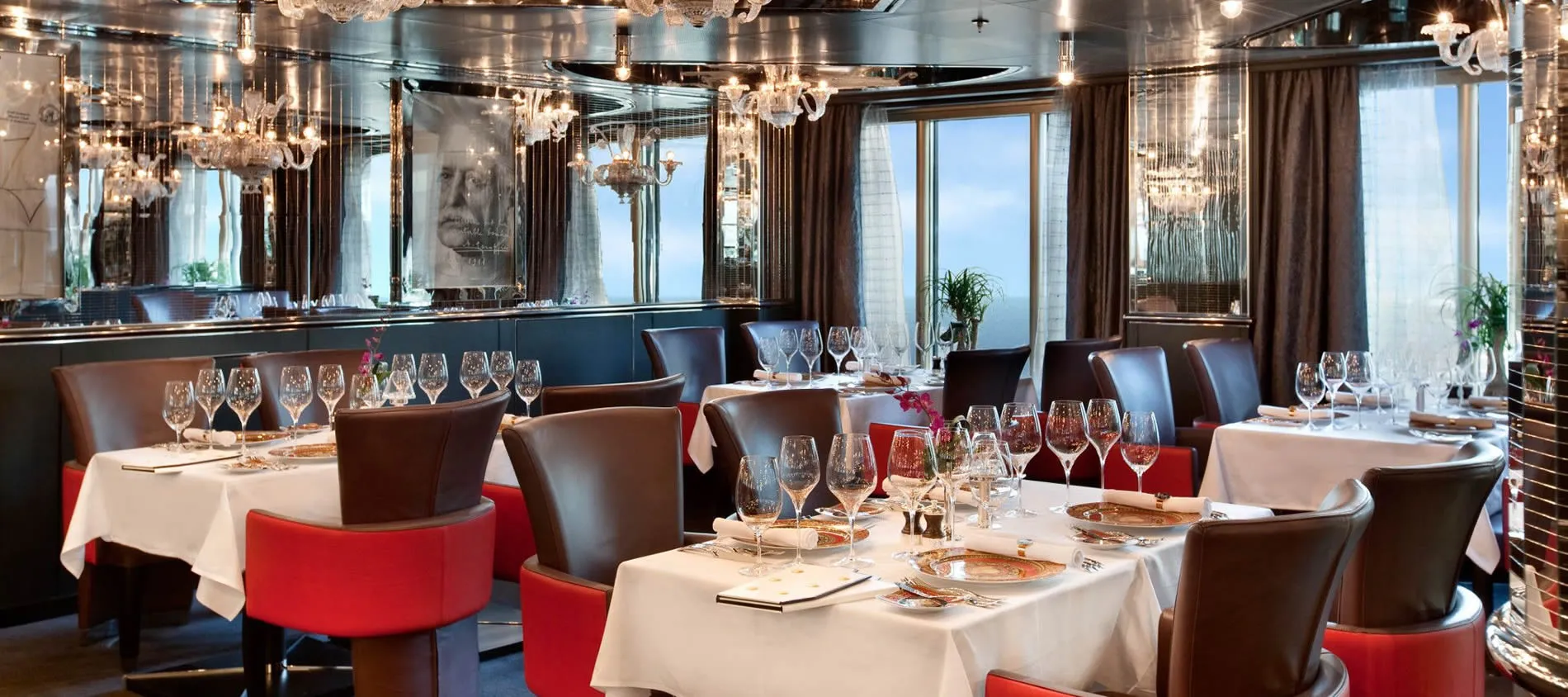 Elegant restaurant interior with chandeliers, white tablecloths, and red chairs