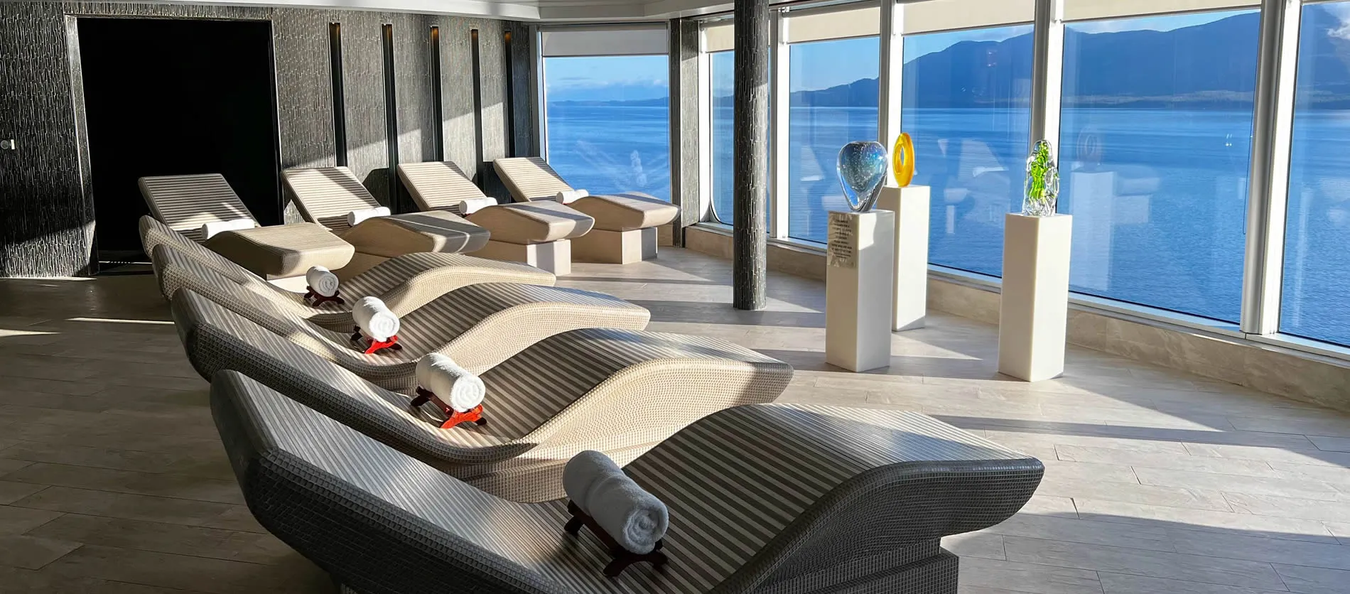 Relaxation room with lounge chairs overlooking scenic ocean and mountain view