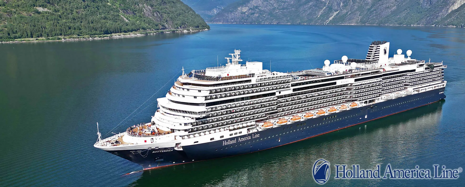 Holland America cruise ship sailing through scenic fjord with mountains