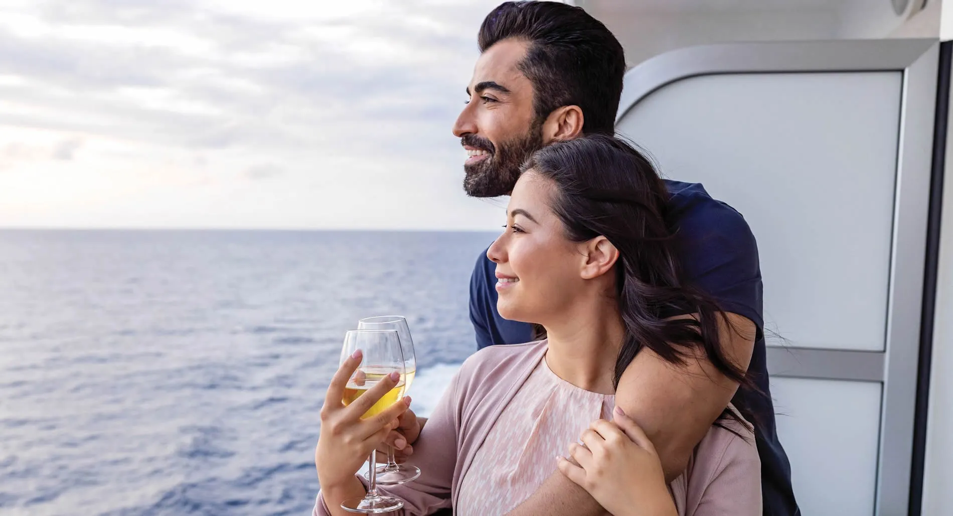 Couple enjoying cruise vacation, drinking wine and looking at ocean view