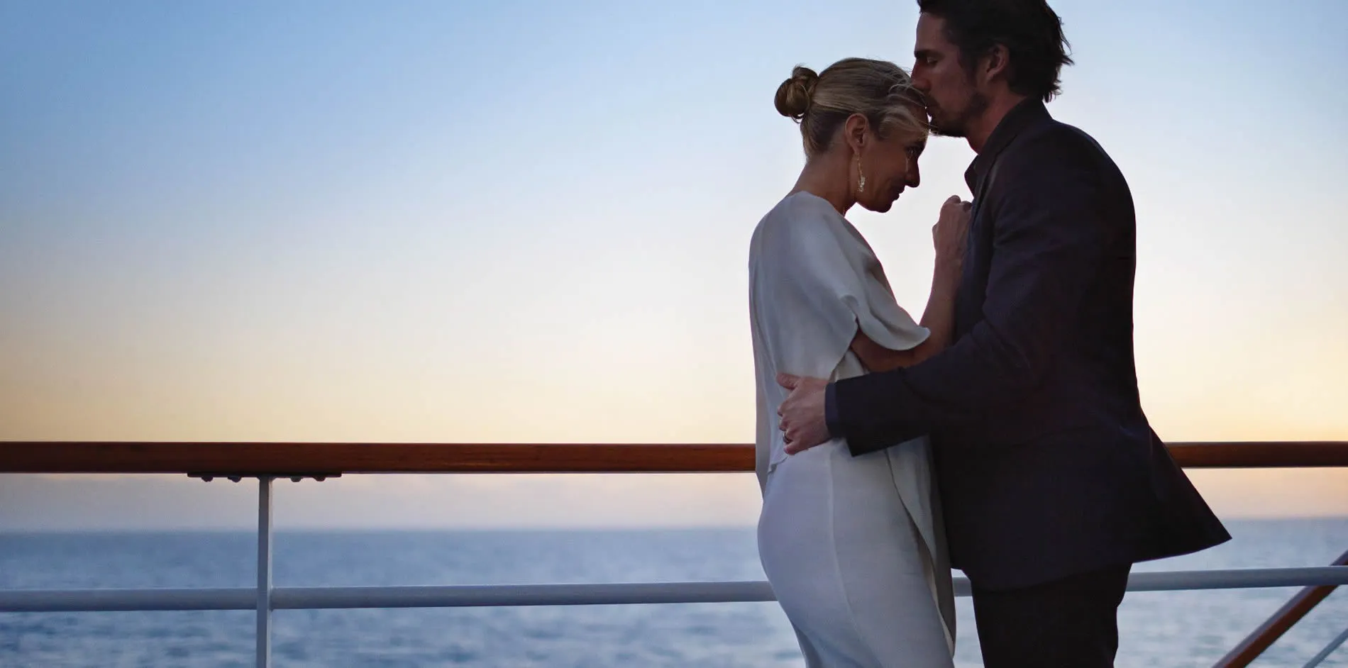 Couple embracing on cruise ship deck at sunset with ocean view