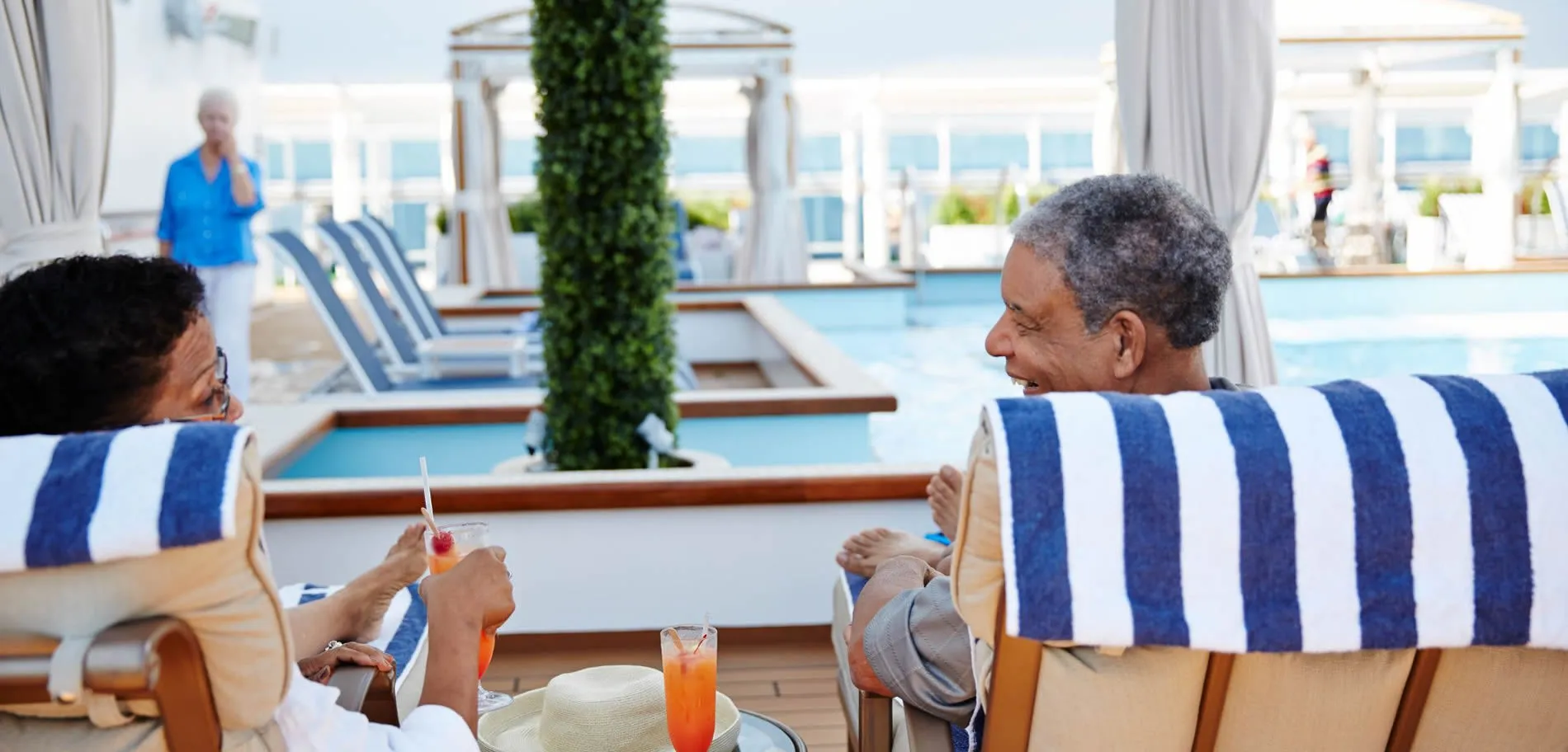 Seniors relaxing with drinks on a cruise ship deck with blue lounge chairs