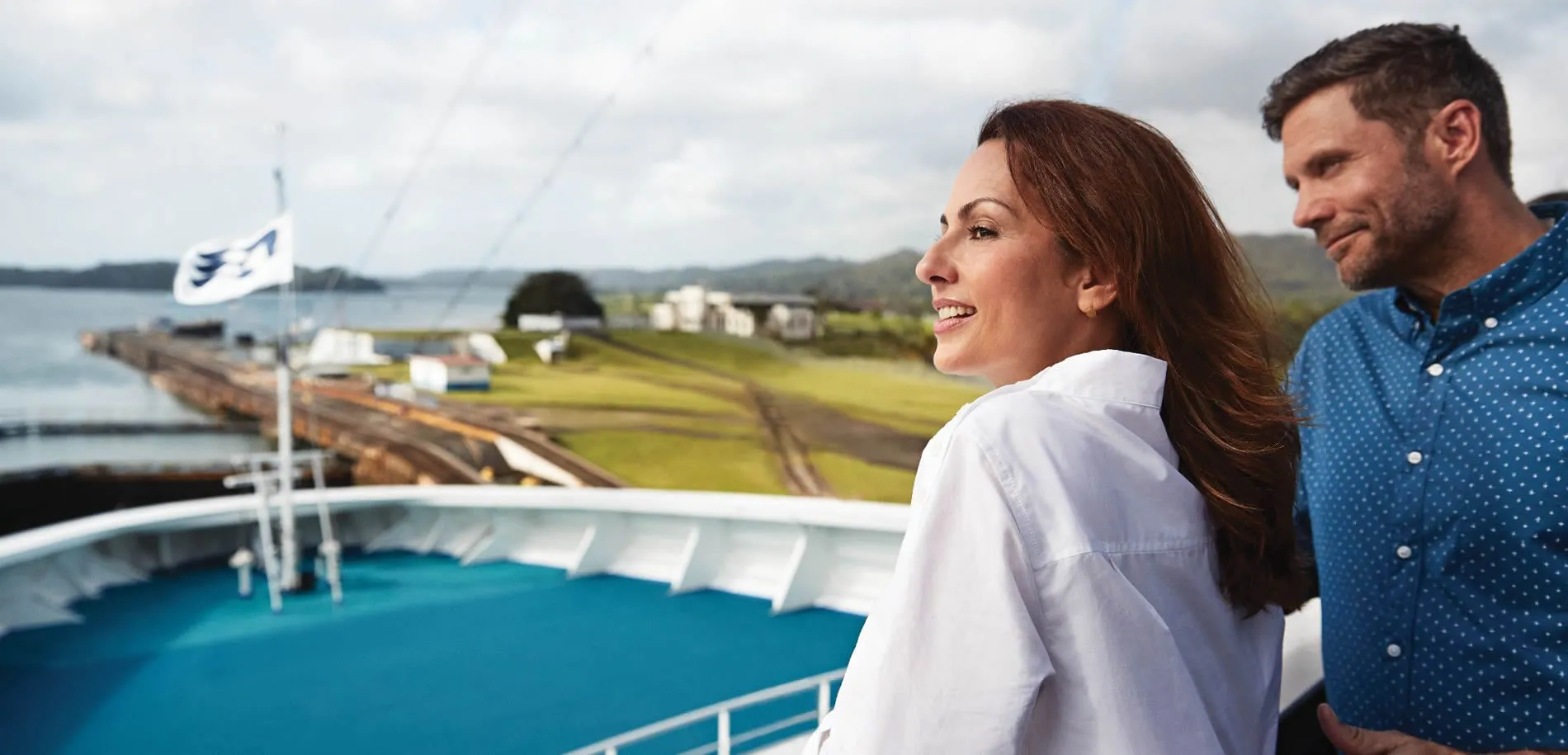 Couple enjoying view from cruise ship deck with scenic landscape
