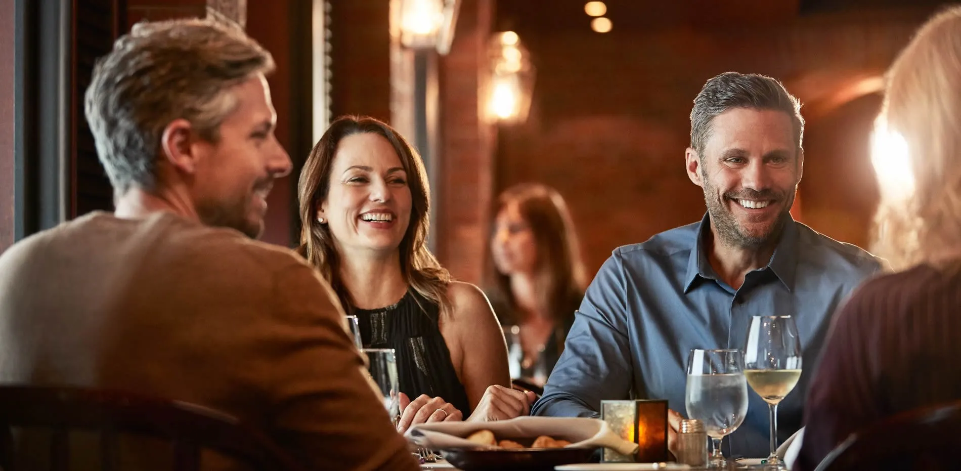 Friends enjoying dinner and wine together at a warm, cozy restaurant