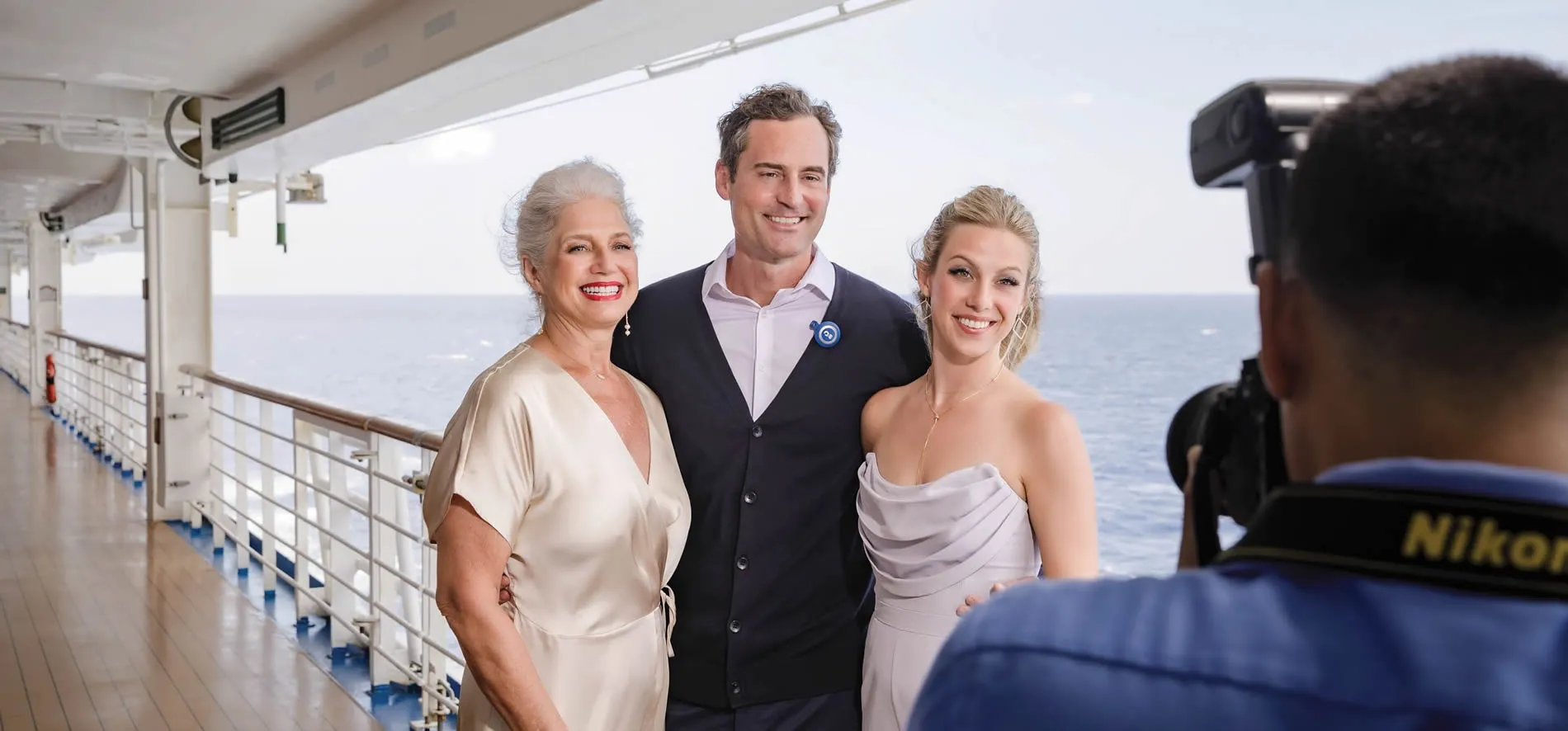 Three people posing on cruise ship deck with ocean in background