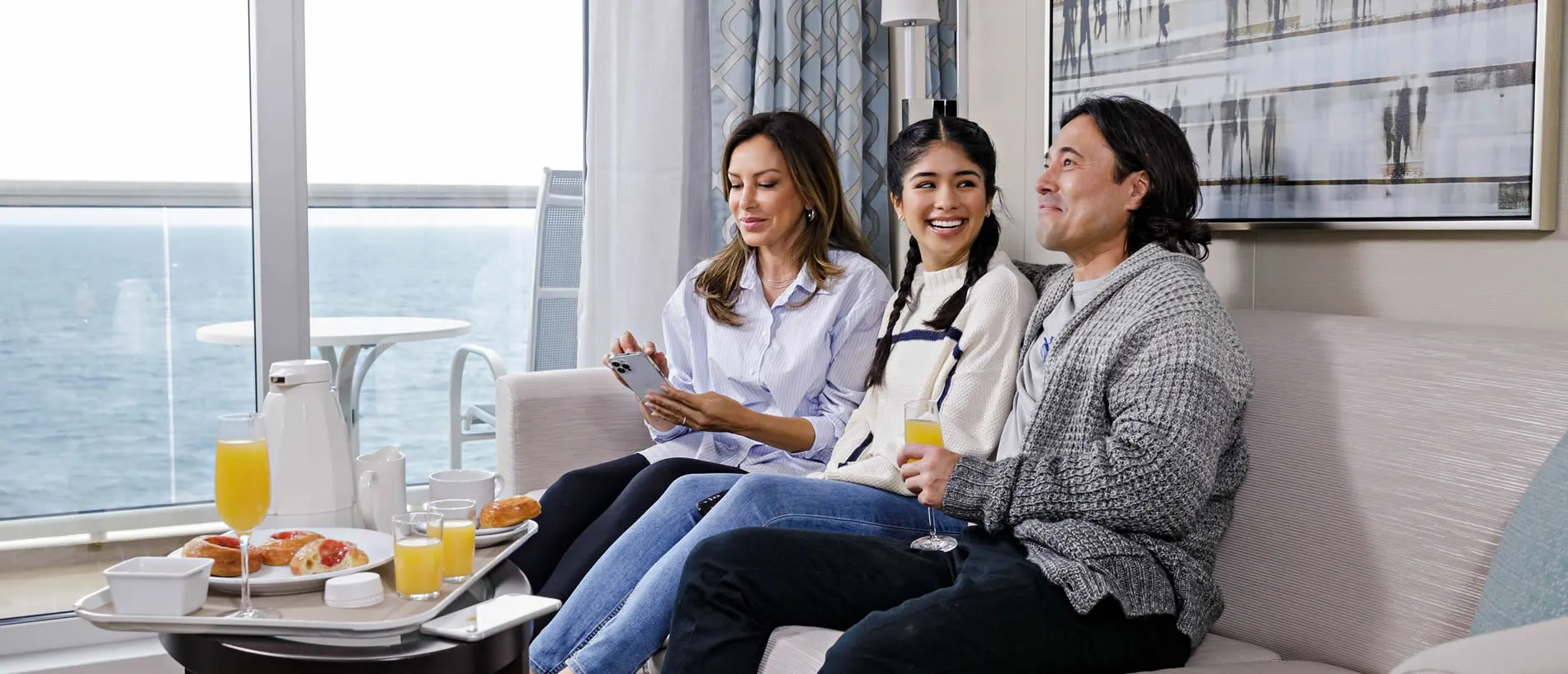 Three people relaxing together on a couch with ocean view and breakfast