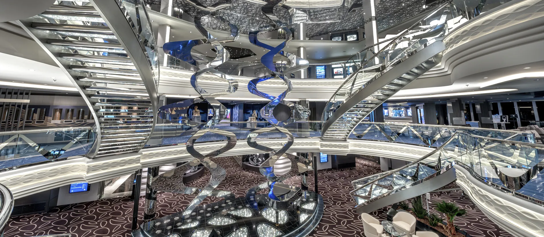 Modern cruise ship interior with sculptural DNA-like blue and silver staircases