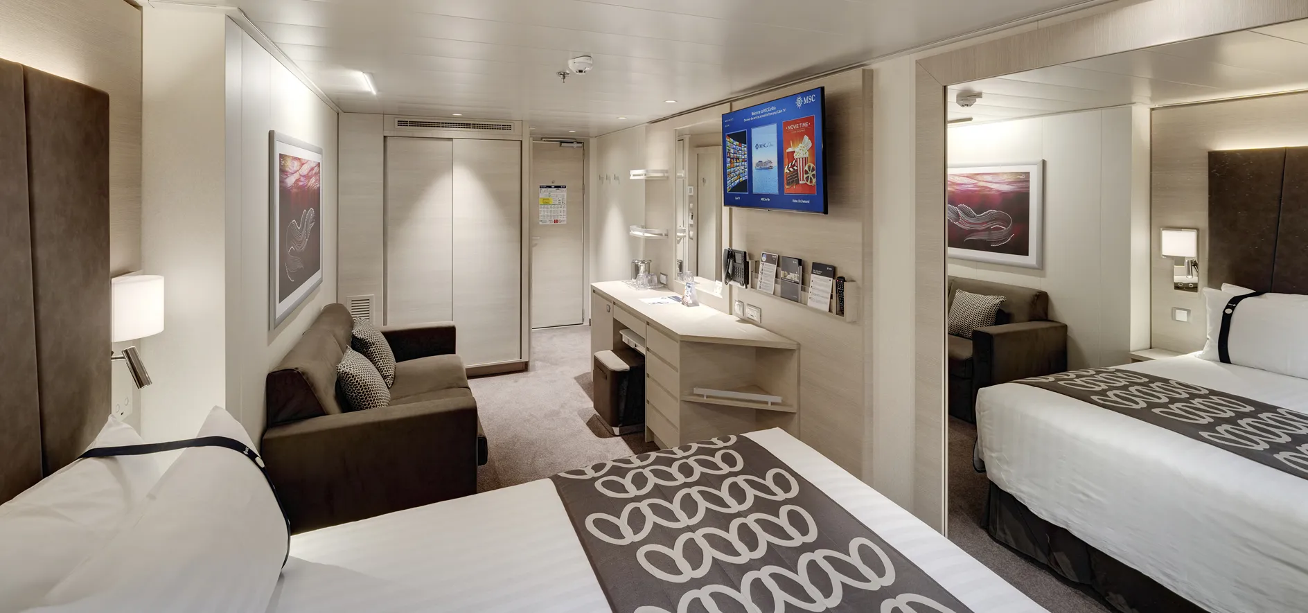 Modern cruise ship cabin with two beds, sofa, and digital display