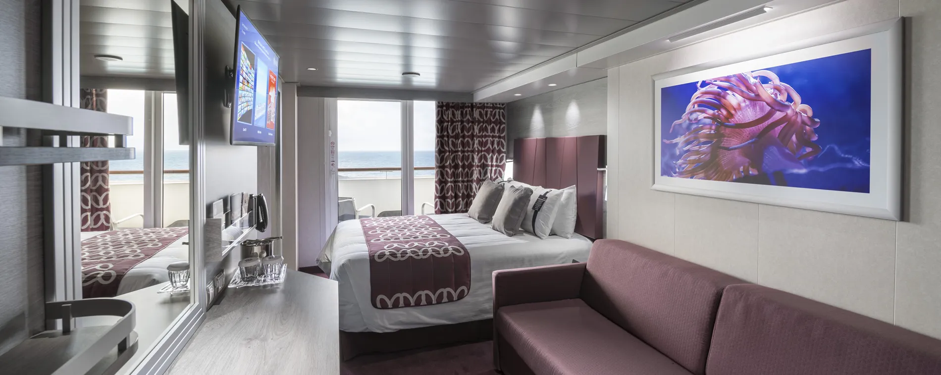Modern cruise ship cabin with ocean view, bed, and artistic sea creature artwork