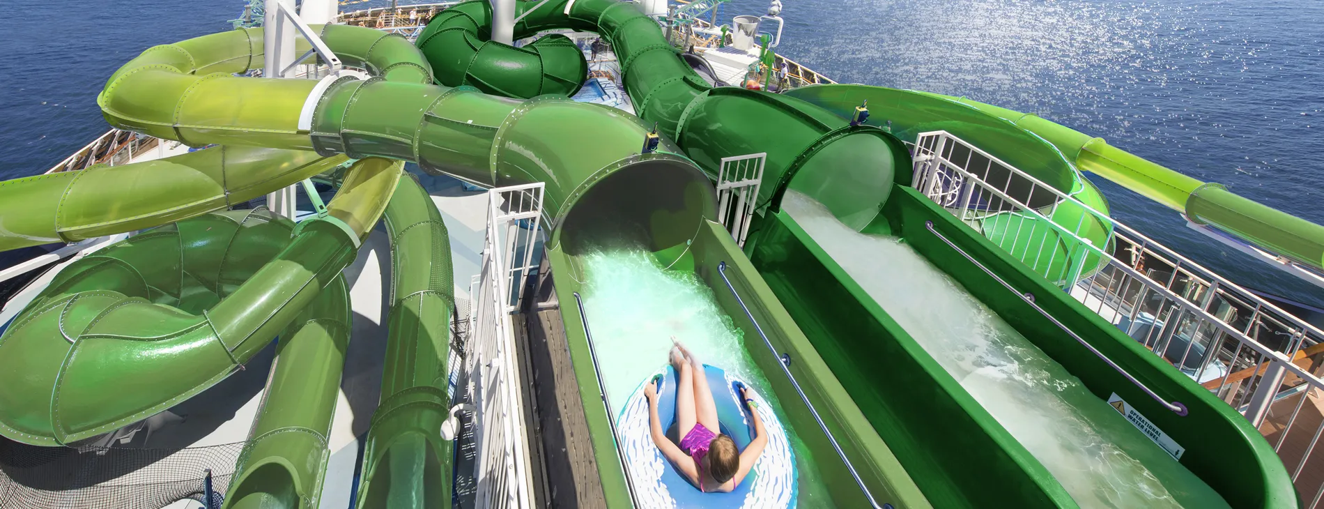 Green water slides on cruise ship with person sliding down