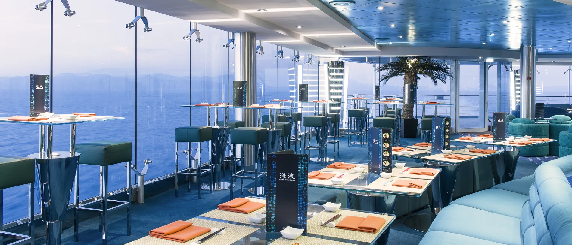 Modern cruise ship restaurant with ocean view and orange table settings