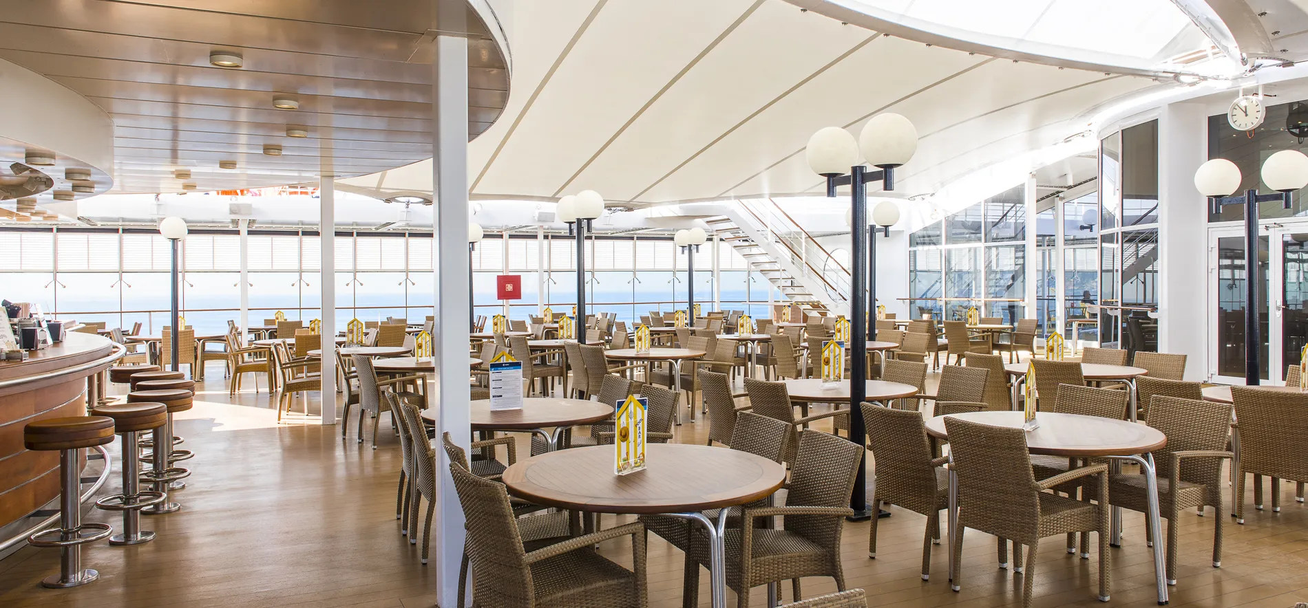 Empty cruise ship dining area with ocean view and round tables