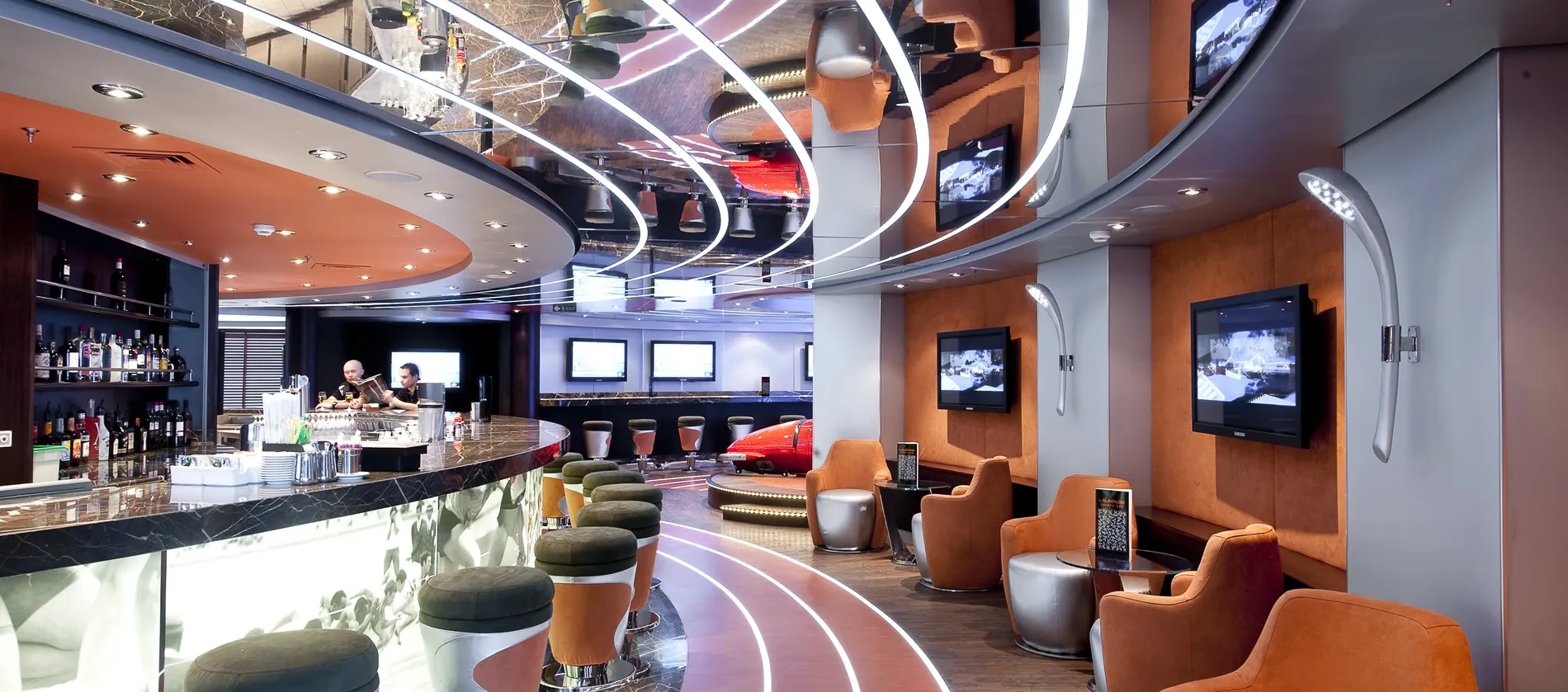 Modern bar with curved design, curved lighting, and stylish orange and silver chairs