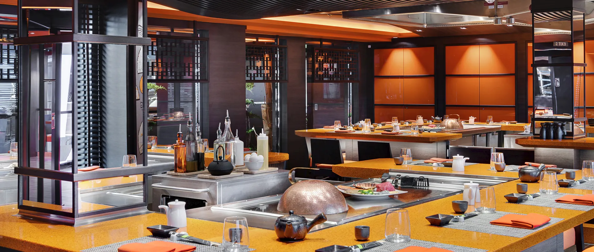 Modern Japanese restaurant with orange tables and cooking stations