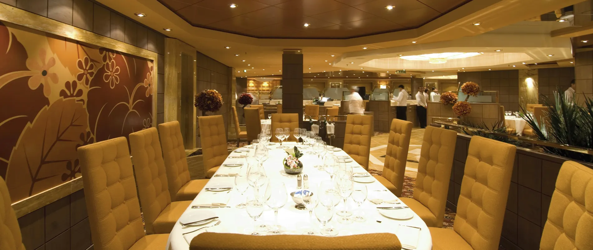 Elegant dining room with long table, yellow chairs, and kitchen in background