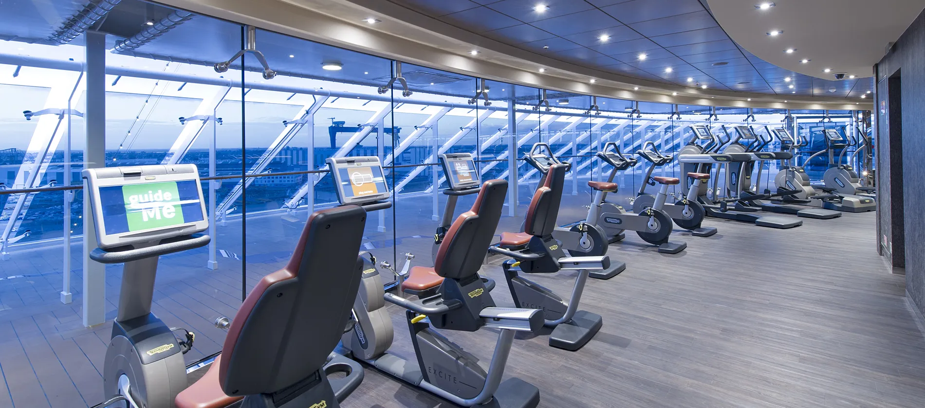 Modern cruise ship gym with exercise bikes and panoramic ocean view