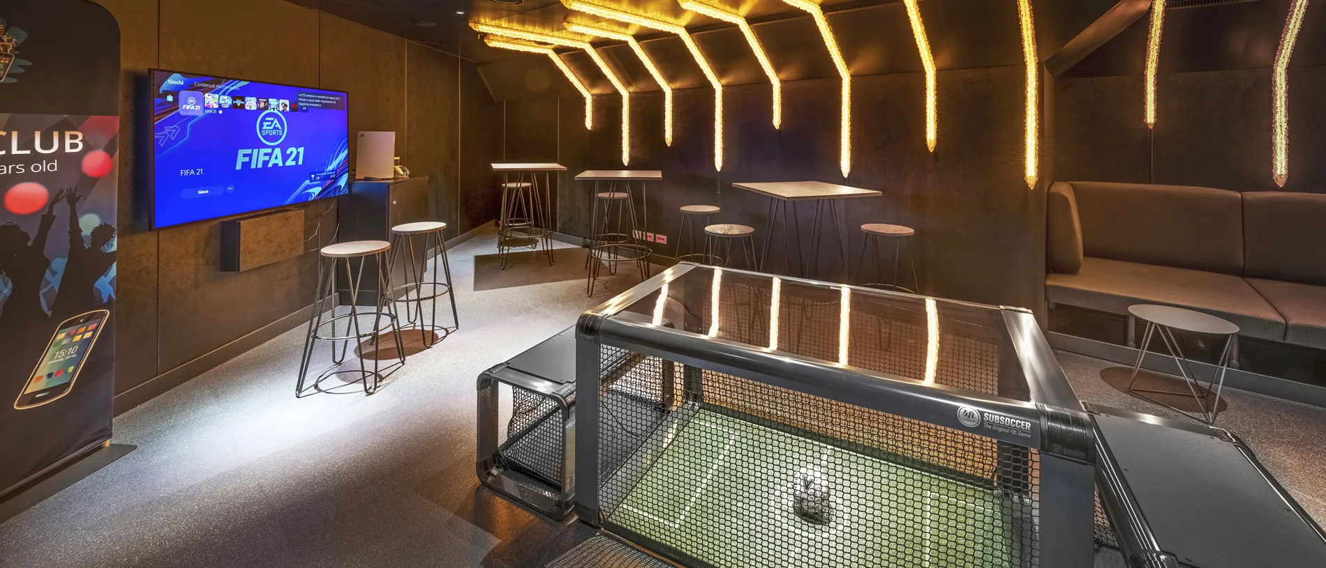 FIFA 21 gaming room with glowing lights, table soccer, and high bar tables