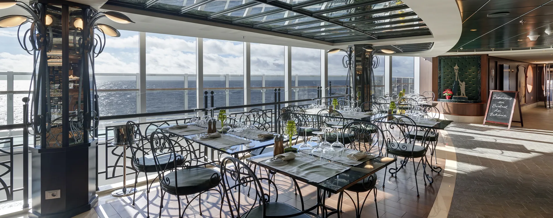 Elegant cruise ship restaurant with ocean view and ornate iron chairs