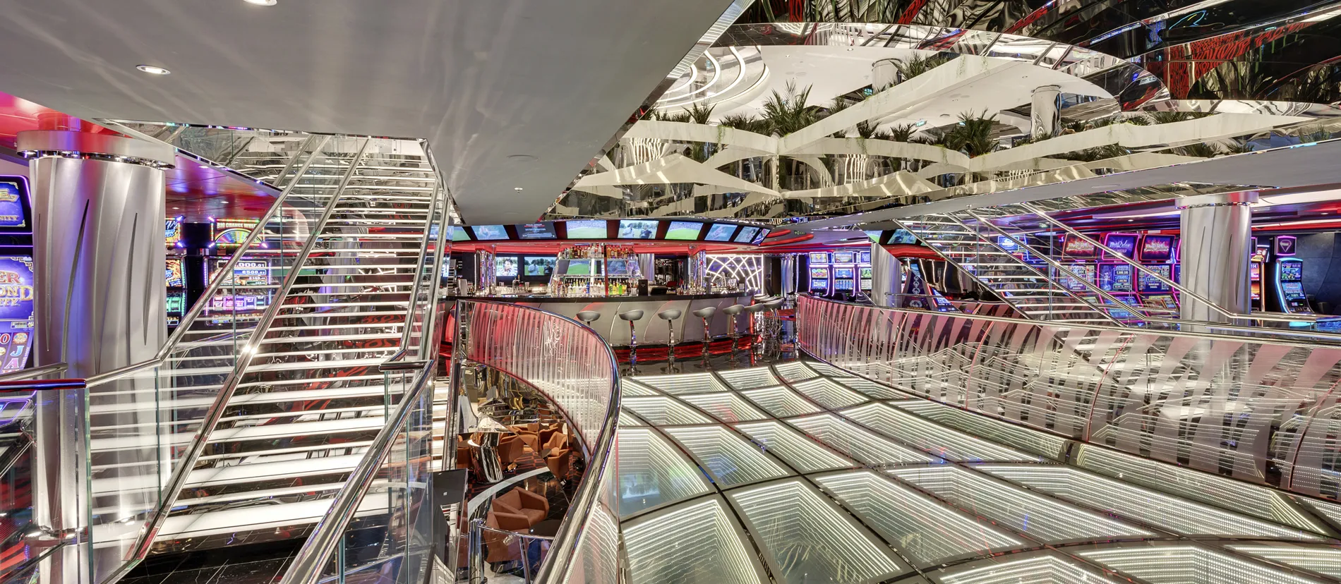 Modern cruise ship casino with multilevel design, glass stairs, and colorful lighting