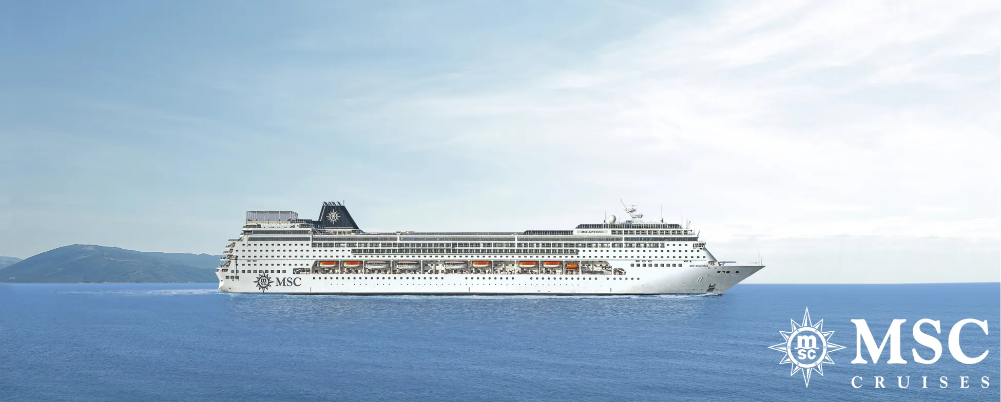 Large white MSC cruise ship sailing on blue sea with mountains in background