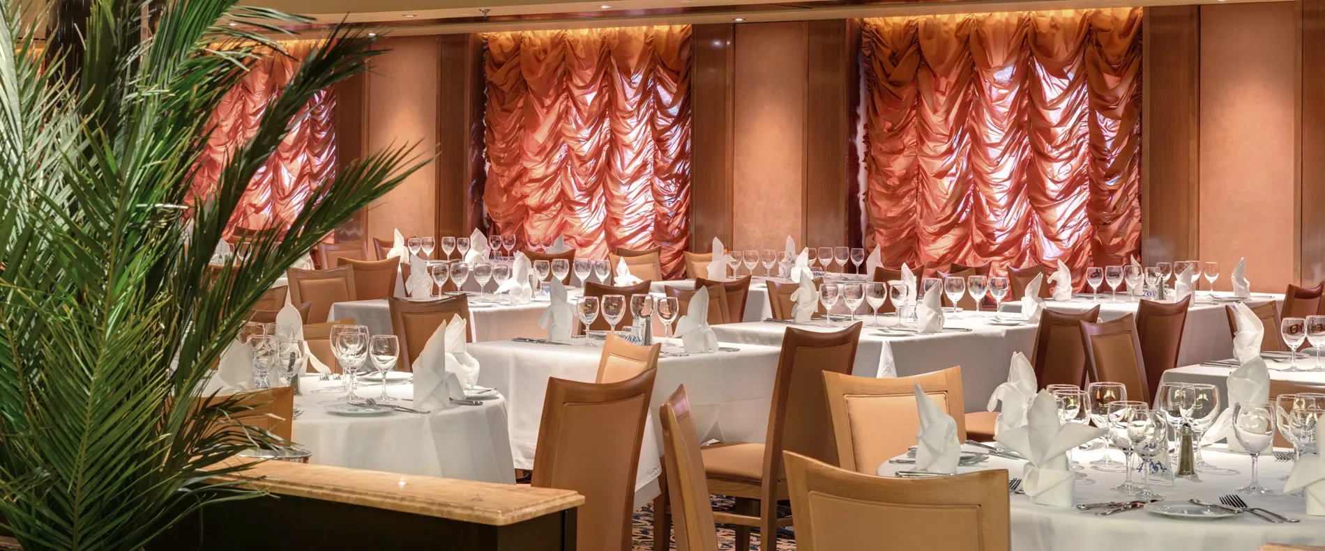 Elegant restaurant dining room with white tablecloths and dramatic red curtains