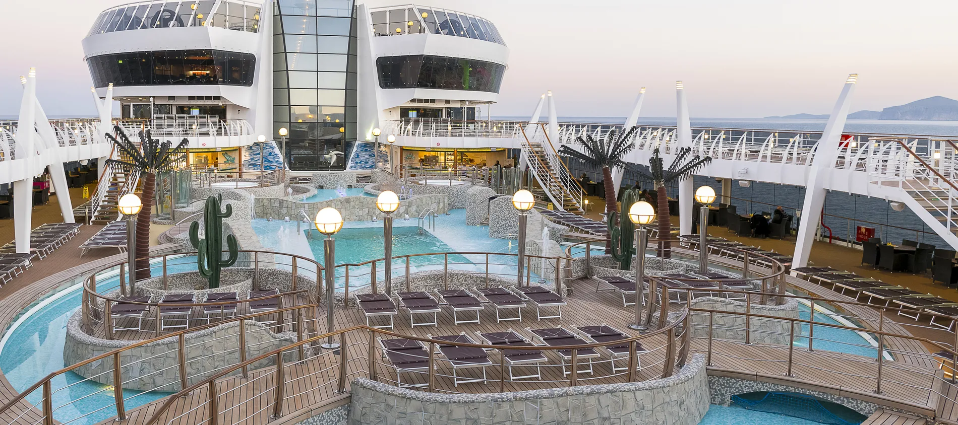 Luxurious cruise ship deck with pools, lounge chairs, and ocean view