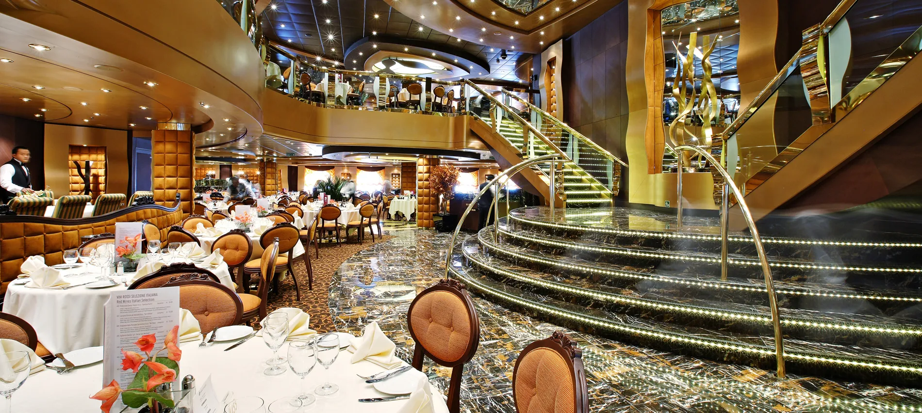 Luxurious cruise ship dining room with elegant tables and curved staircase