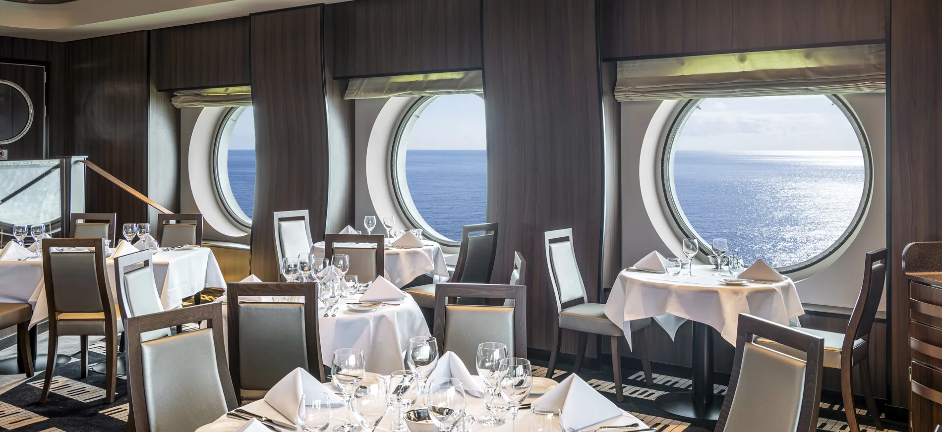 Elegant cruise ship dining room with ocean view through round windows