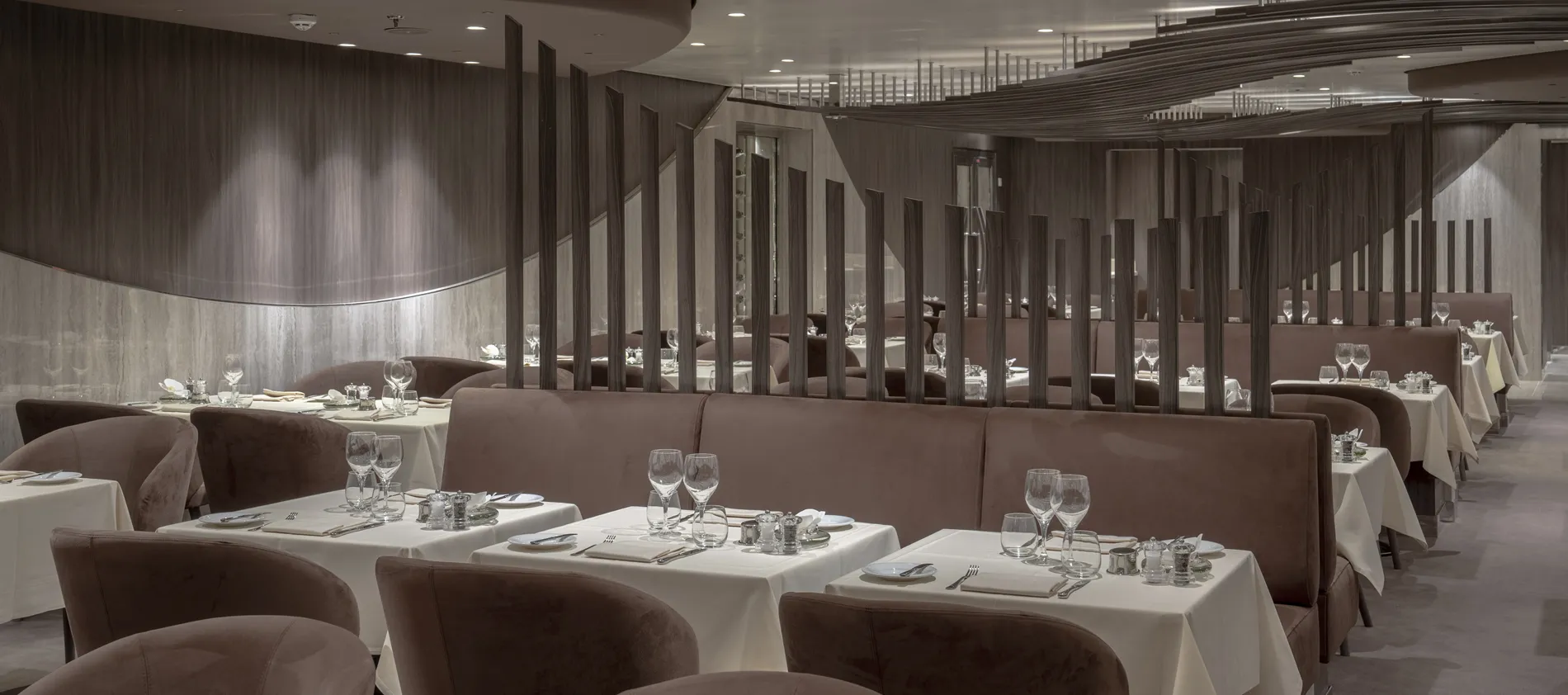 Elegant restaurant interior with white tablecloths, brown chairs, and wine glasses