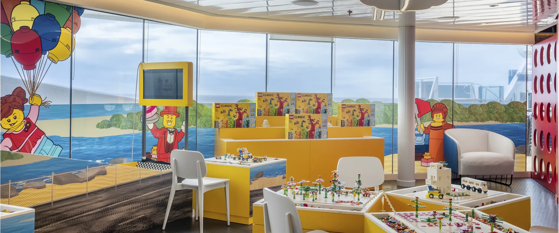 LEGO store interior with ocean view, yellow displays, and classic building sets