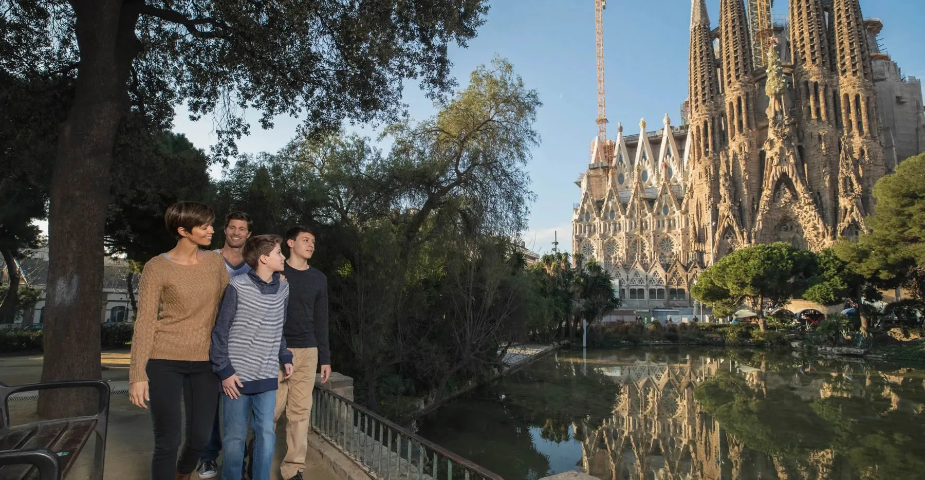 Family standing near Sagrada Familia in Barcelona with water reflection