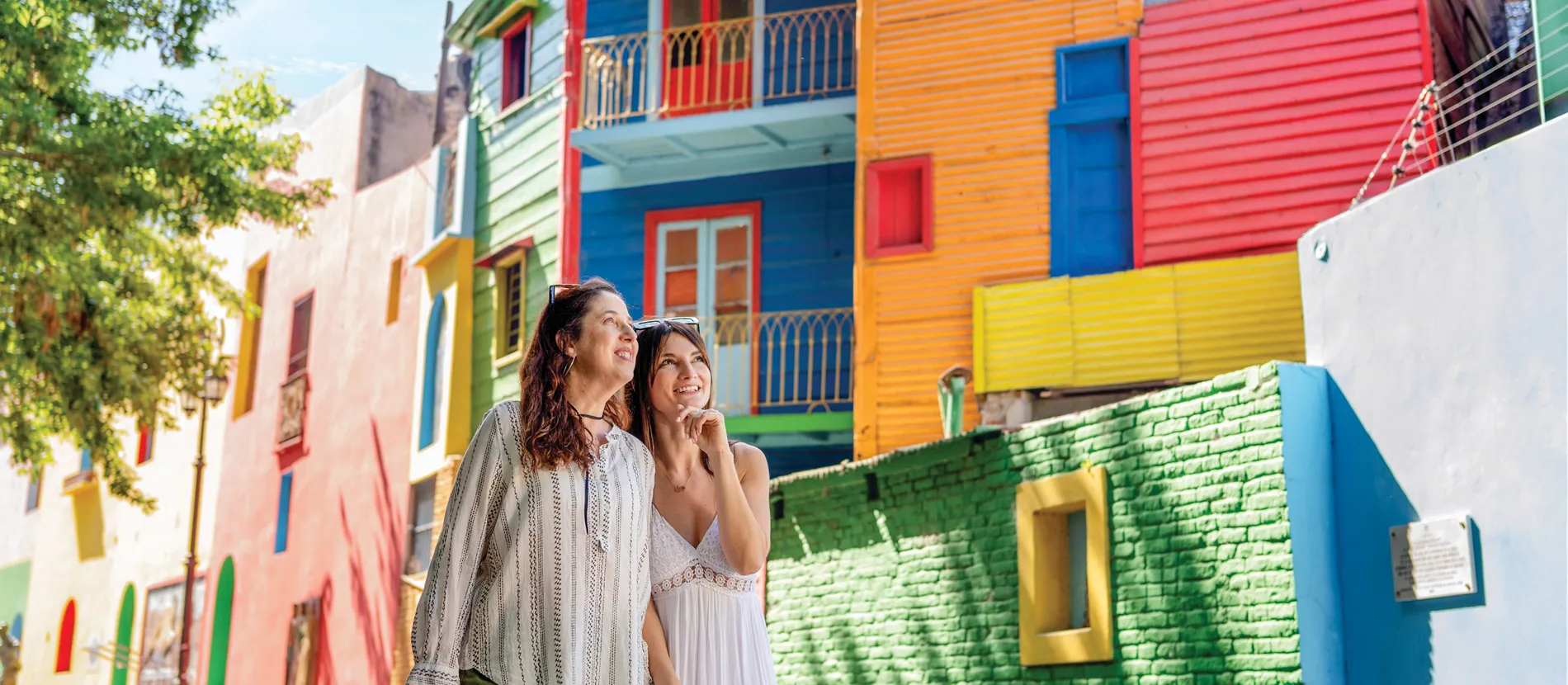 Two women walking in front of colorful buildings in vibrant neighborhood