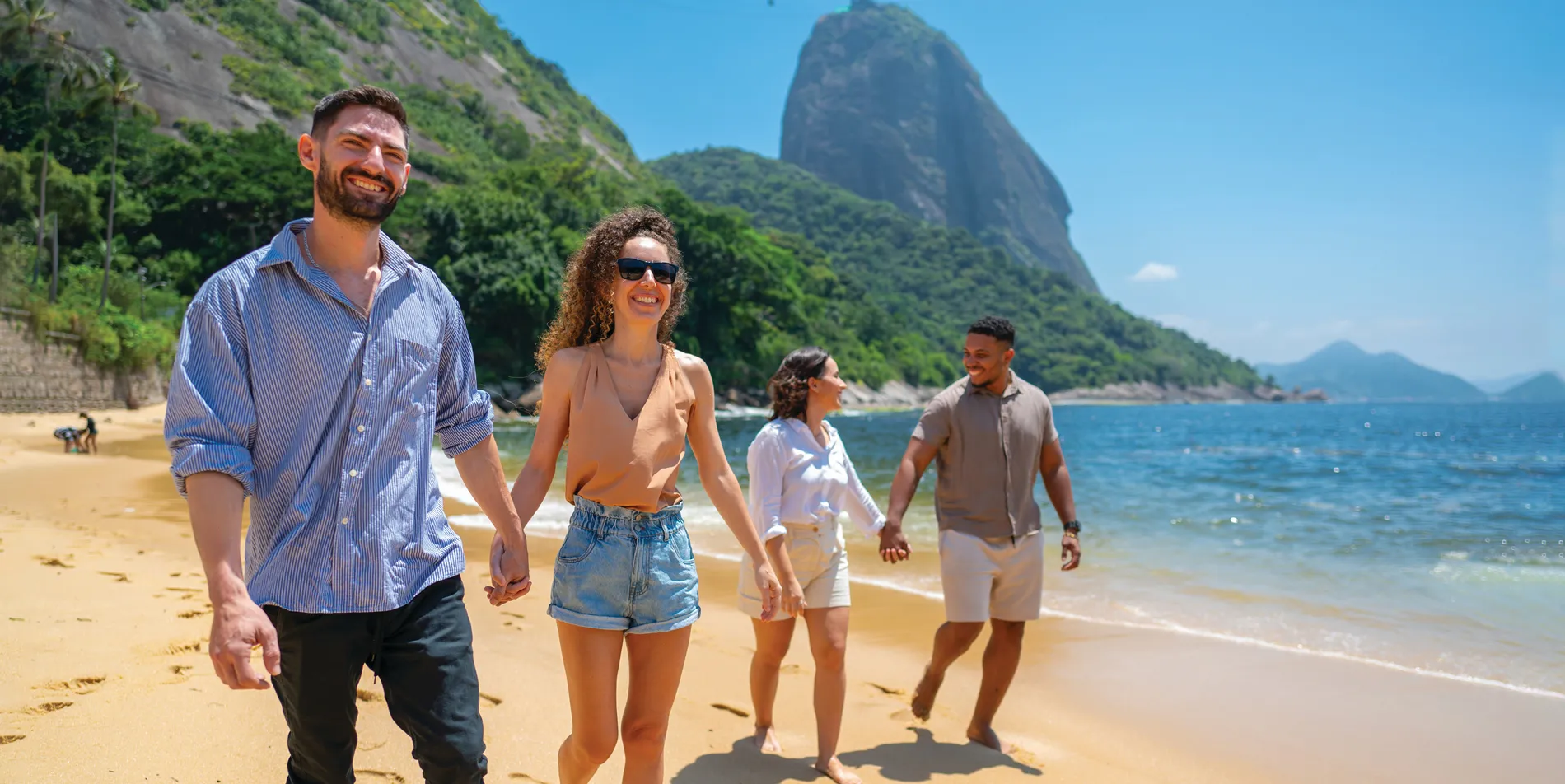 Friends walking on beach with Sugarloaf Mountain in Rio de Janeiro background