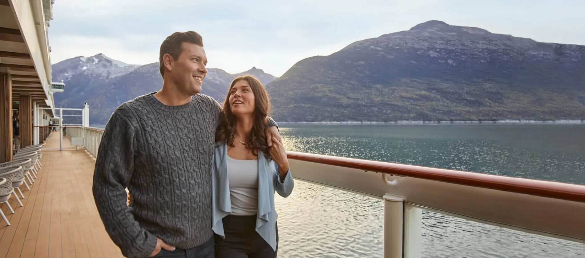Couple enjoying scenic cruise with mountains and lake in background