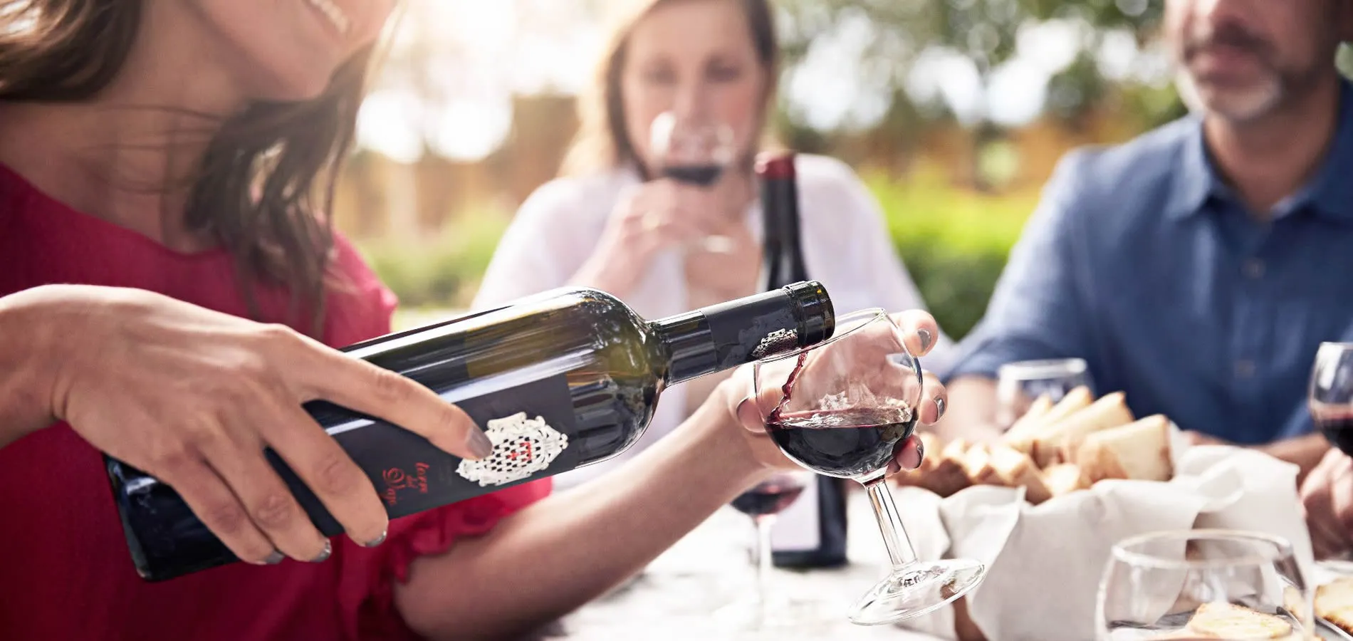Pouring red wine during outdoor social gathering with friends