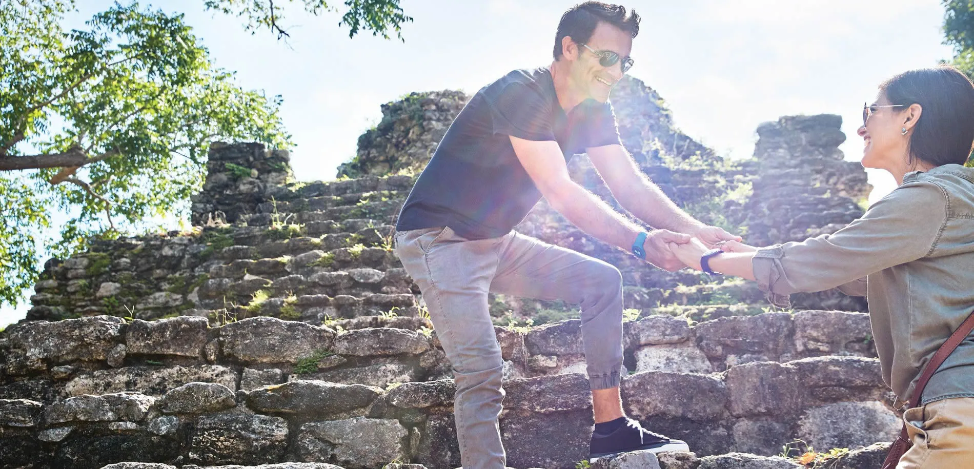 Tourists exploring ancient stone ruins with sunlight and trees