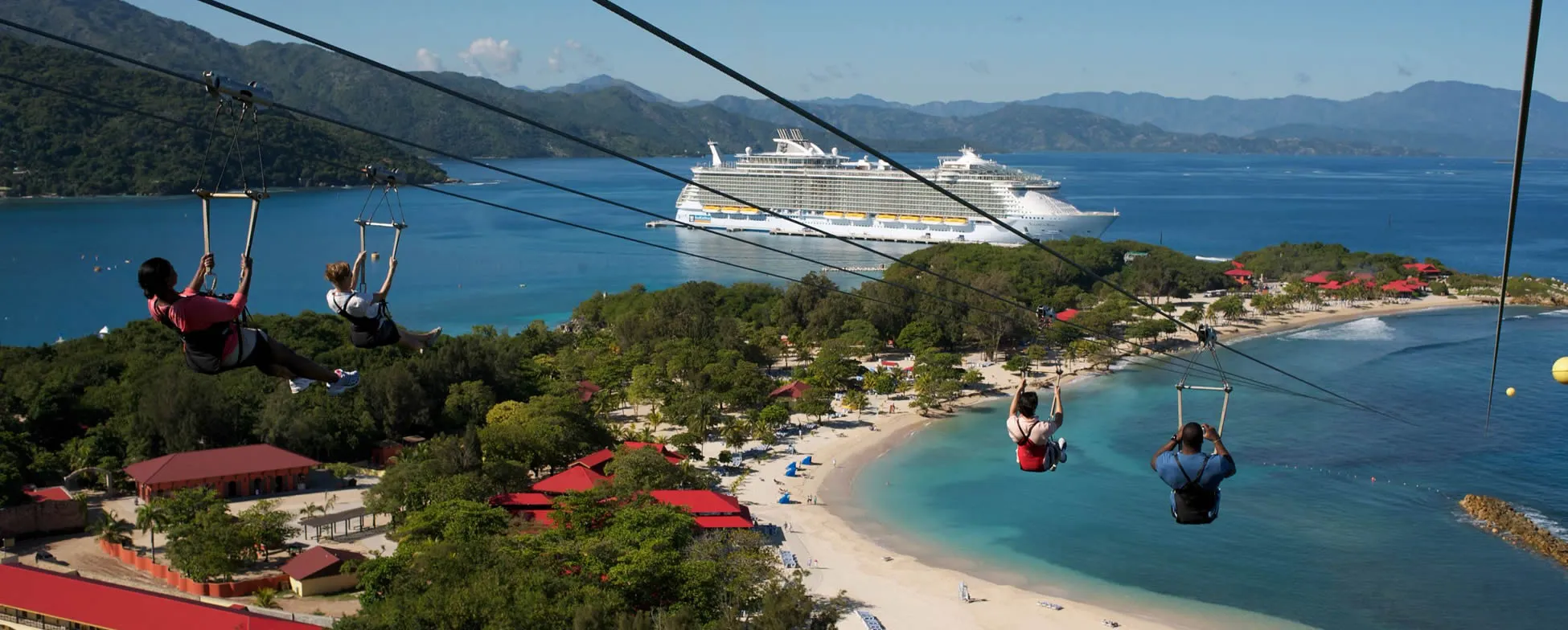 Zipliners overlooking tropical beach with cruise ship in background