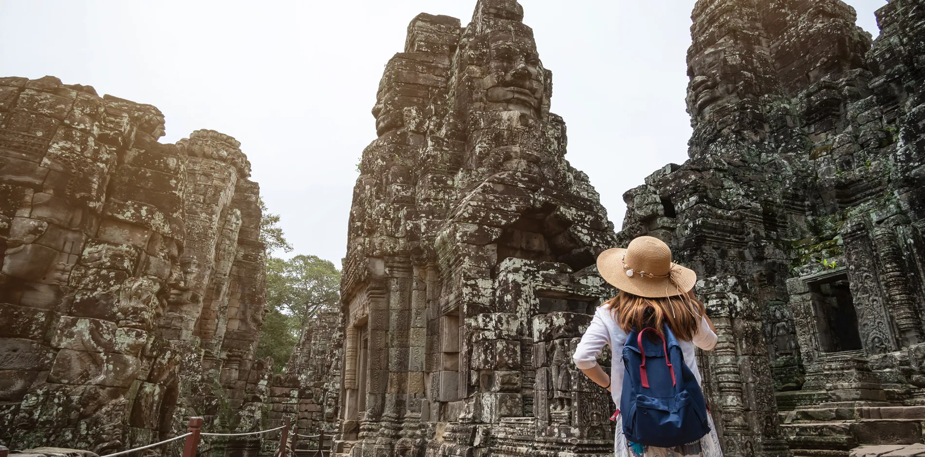 Tourist with backpack exploring ancient Bayon Temple in Angkor Wat, Cambodia