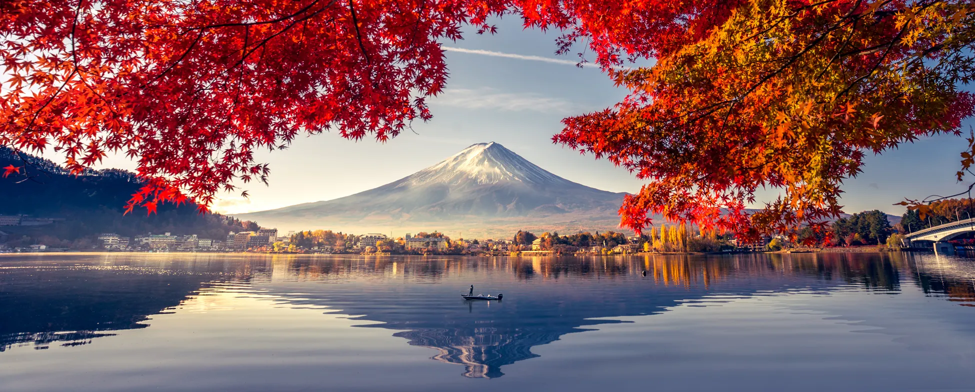 Autumn view of Mount Fuji with red maple trees and calm lake reflection