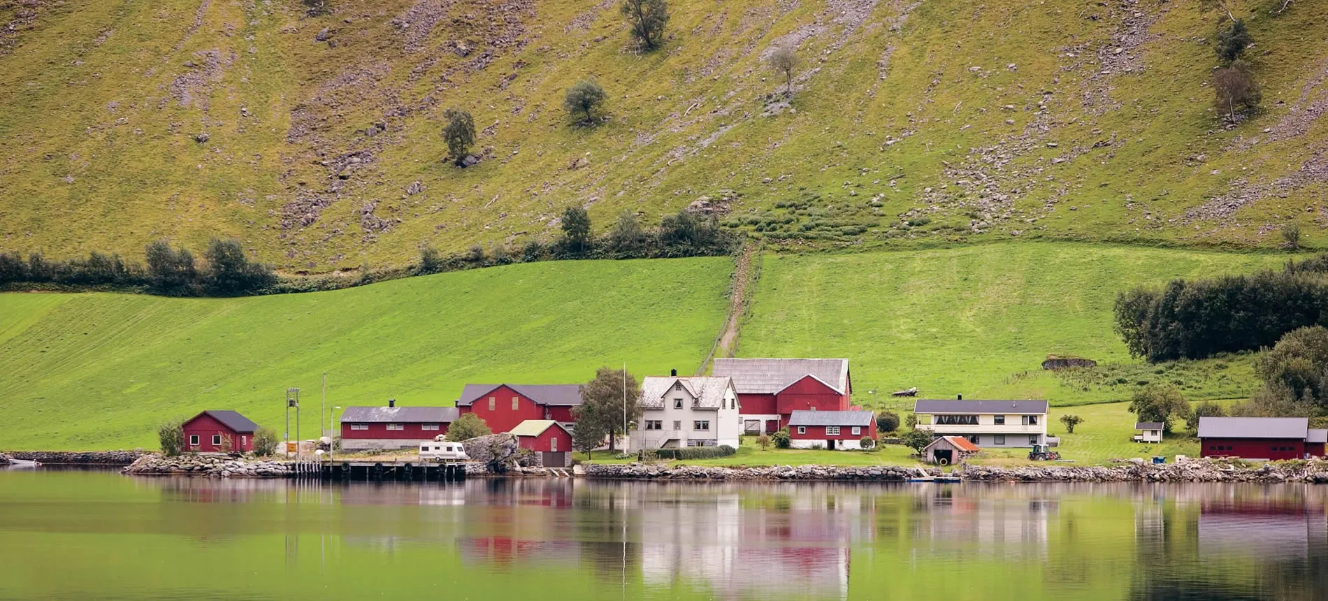 Peaceful Norwegian fjord village with red houses nestled by green hills